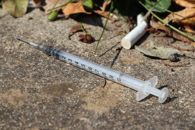 Used and discarded syringe and needle on the street. Used and discarded syringe and needle on the street