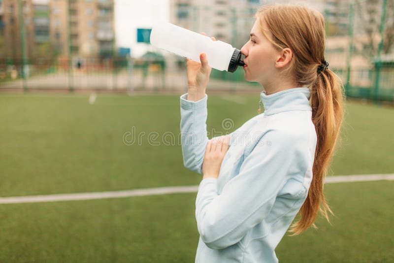 在训练,跑或者体育以后的女孩在前景,一个瓶的休息水 女孩在开放,新鲜空气工作 免版税图库摄影 在训练,跑或者体育以后的女孩在前景,一个瓶的休息水 女孩在开放,新鲜空气工作 免版税图库摄影