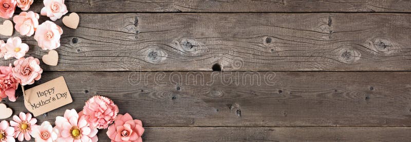 Happy Mothers Day corner border with paper flowers and gift tag. Overhead view against a rustic wood banner background. Copy space. Happy Mothers Day corner border with paper flowers and gift tag. Overhead view against a rustic wood banner background. Copy space