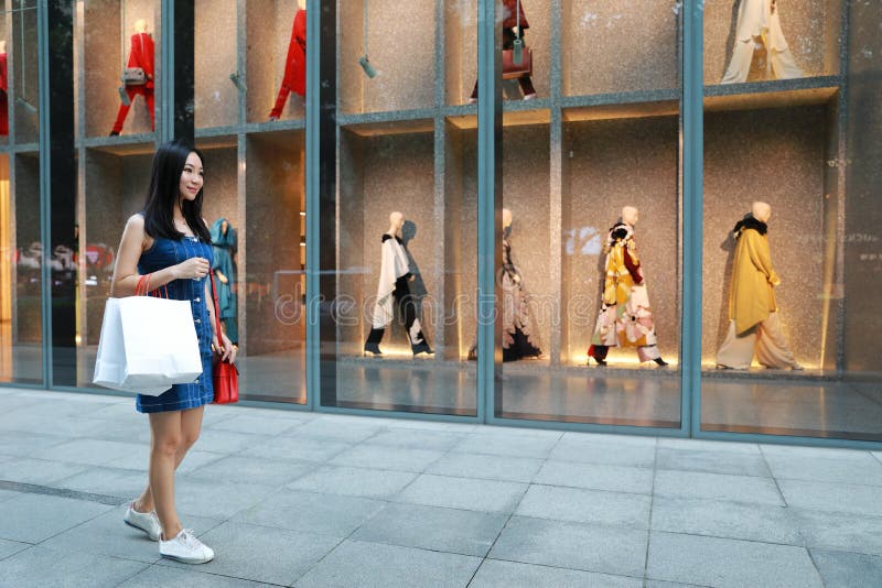 在购物中心的愉快的亚洲中国东部东方年轻时髦妇女女孩购物有在街道城市的袋子购物的窗口背景 库存图片 在购物中心的愉快的亚洲中国东部东方年轻时髦妇女女孩购物有在街道城市的袋子购物的窗口背景 库存图片