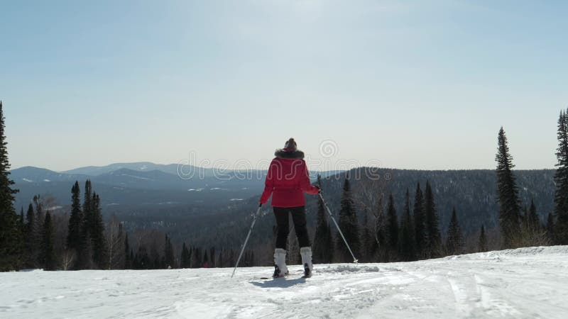 在阳光明媚的冬季滑雪场滑雪的运动女子