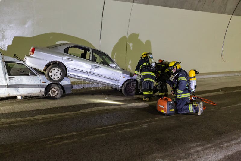 在隧道里面的车祸场面，抢救从汽车的消防队员人 免版税库存图片