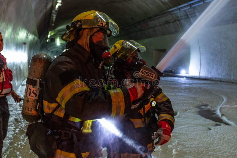 在隧道里面的车祸场面，抢救从汽车的消防队员人 免版税库存照片