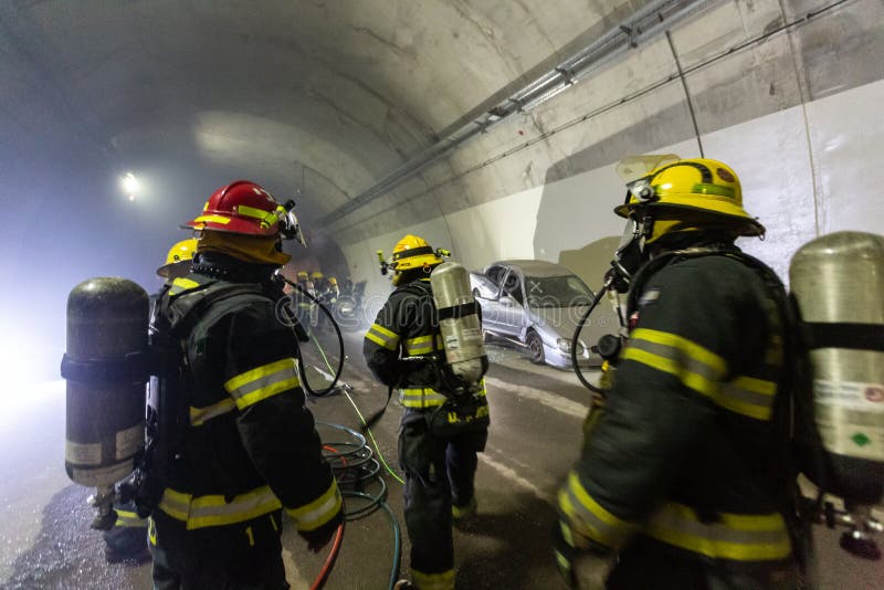 在隧道里面的车祸场面，抢救从汽车的消防队员人 库存图片