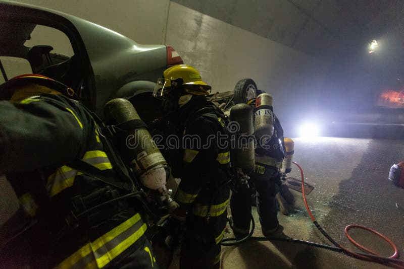 在隧道里面的车祸场面，抢救从汽车的消防队员人 图库摄影