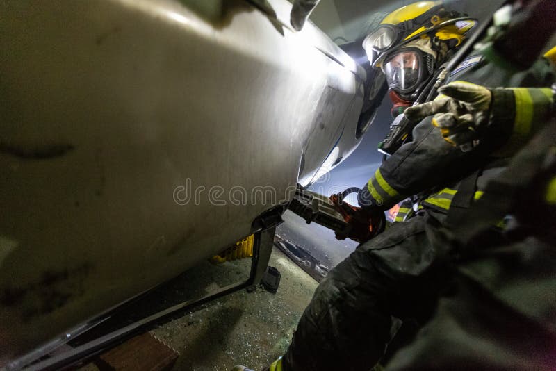 在隧道里面的车祸场面，抢救从汽车的消防队员人 图库摄影