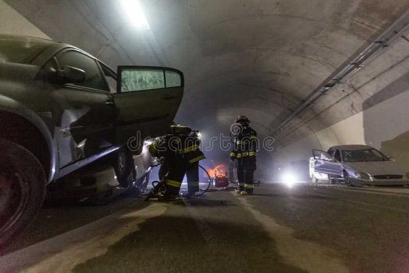 在隧道里面的车祸场面，抢救从汽车的消防队员人 免版税库存图片