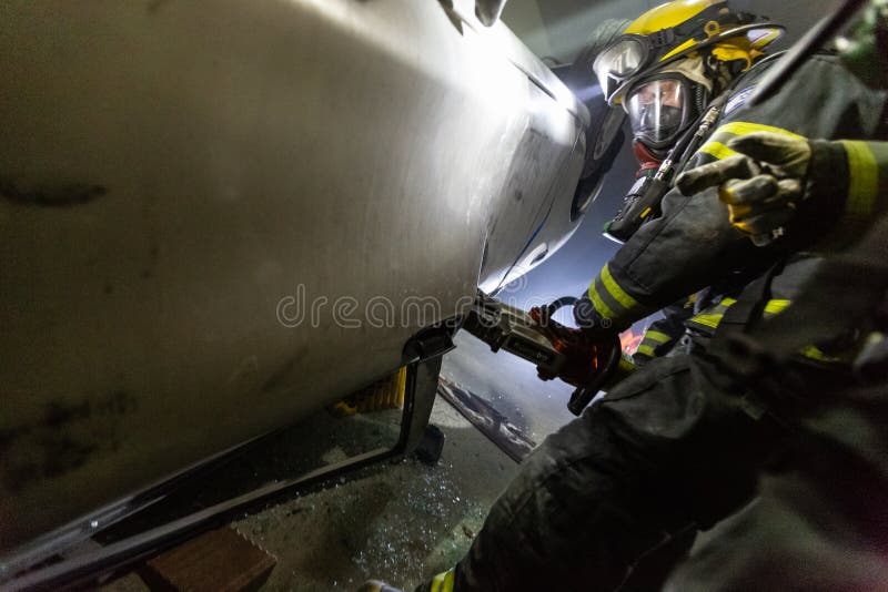 在隧道里面的车祸场面，抢救从汽车的消防队员人 图库摄影