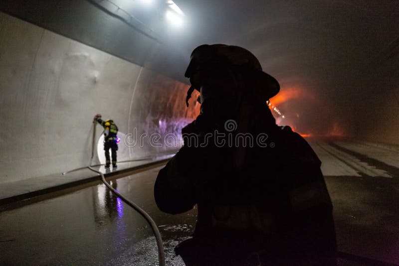 在隧道里面的车祸场面，抢救从汽车的消防队员人 免版税库存图片