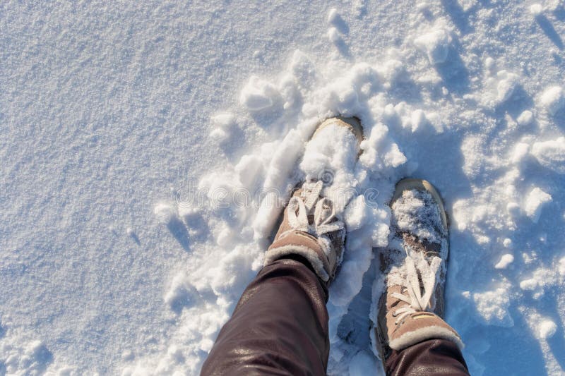 在雪地中穿着冬靴的女性. 适合户外散步和在寒冷天气旅行的舒适温暖鞋 免版税图库摄影