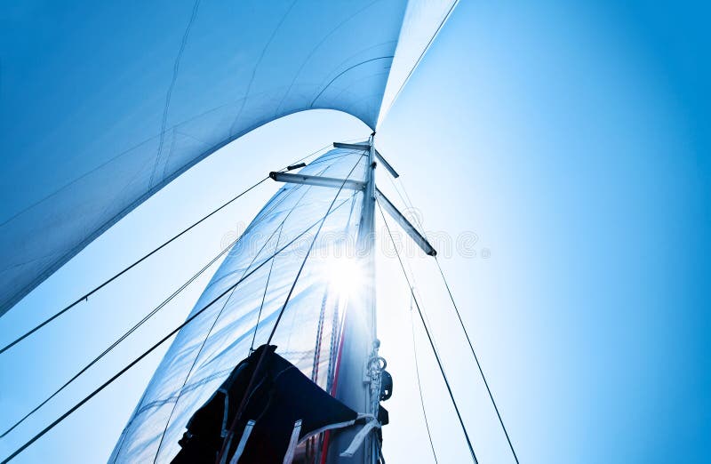 Sail over clear blue sky, sailboat over natural background with sunlight, summertime activities and extreme sport. Sail over clear blue sky, sailboat over natural background with sunlight, summertime activities and extreme sport