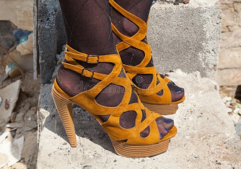 Woman`s feet in high heel sandals on the concrete stairs. Woman`s feet in high heel sandals on the concrete stairs