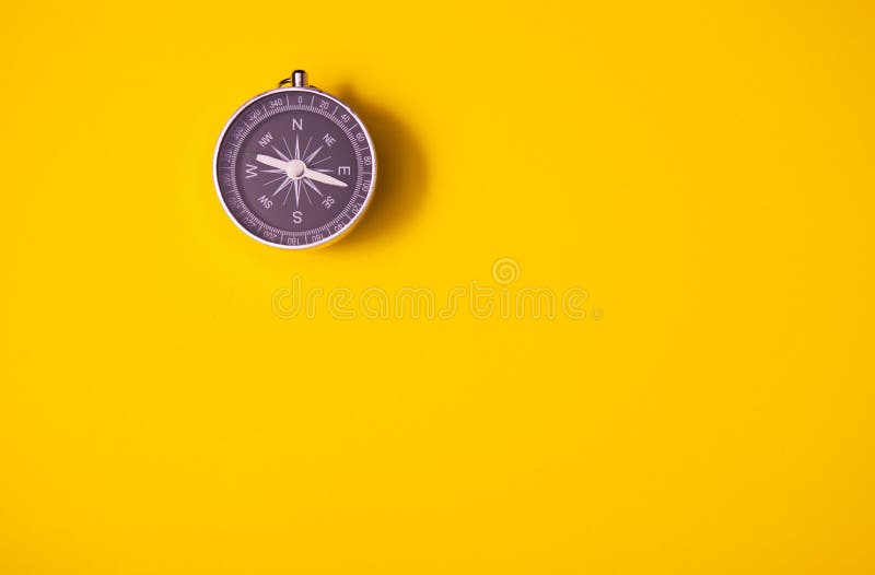 在黄色背景的黑旅行的指南针，设备，旅游业和事务、顶视图和拷贝空间 库存图片