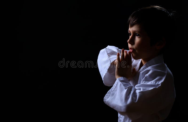 在黑暗的背景隔绝的白色和服的一点空手道孩子 男孩画象准备好武道战斗 战斗在的孩子 库存图片 在黑暗的背景隔绝的白色和服的一点空手道孩子 男孩画象准备好武道战斗 战斗在的孩子 库存图片