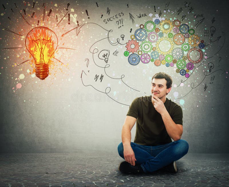 Cheerful man sitting on the floor smiling looking at a bright light bulb on the wall. Idea concept, positive thinking as colorful gear brain above head, create a genius. Mental development symbol. Cheerful man sitting on the floor smiling looking at a bright light bulb on the wall. Idea concept, positive thinking as colorful gear brain above head, create a genius. Mental development symbol