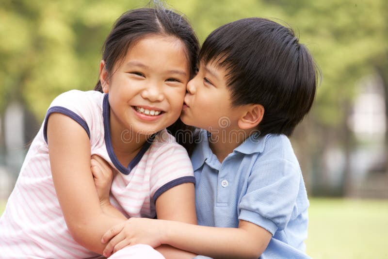 坐在公园的中国男孩和女孩纵向 免版税库存图片
