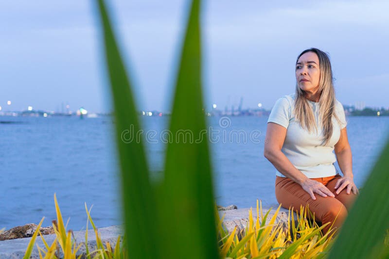 坐在公园里沉醉的成熟的拉丁裔女性 图库摄影