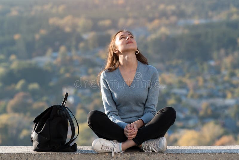 坐在大自然中,望着天空,享受生活的年轻女人 前视图 图库摄影 坐在大自然中,望着天空,享受生活的年轻女人 前视图 图库摄影