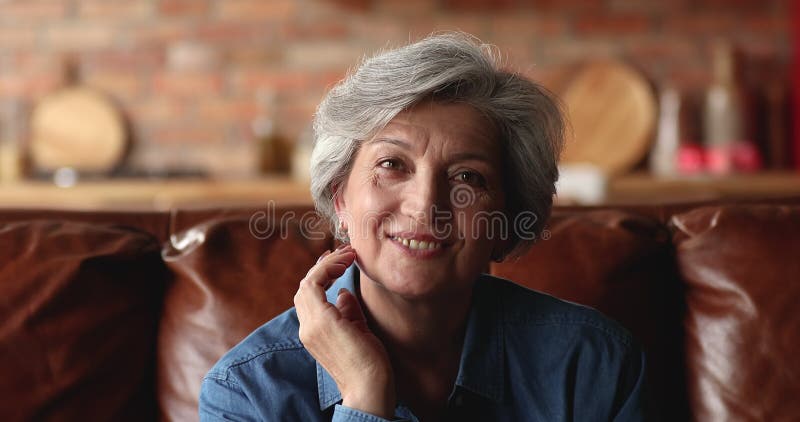 坐在沙发上、面带微笑地看着相机的年迈女性