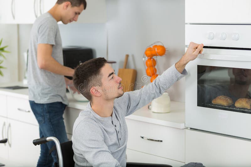 坐在厨房里的轮椅上的男人 库存照片
