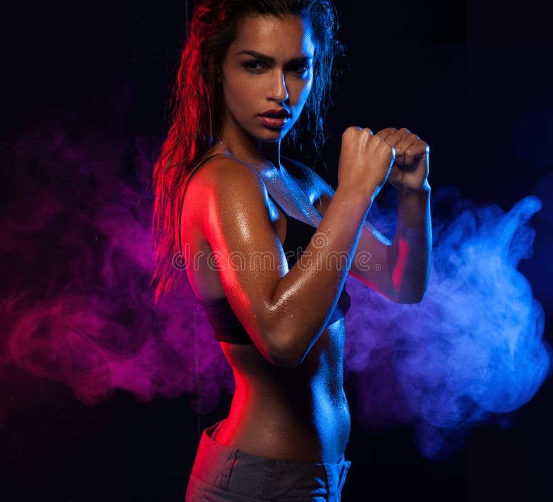 Determined fit woman working out on blue and violet smoky wave background. Determined fit woman working out on blue and violet smoky wave background