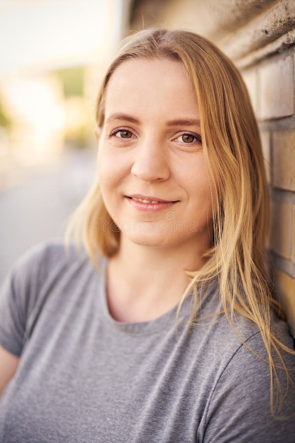 城市街道上年轻的欢快的千禧一代女子的肖像 免版税库存照片