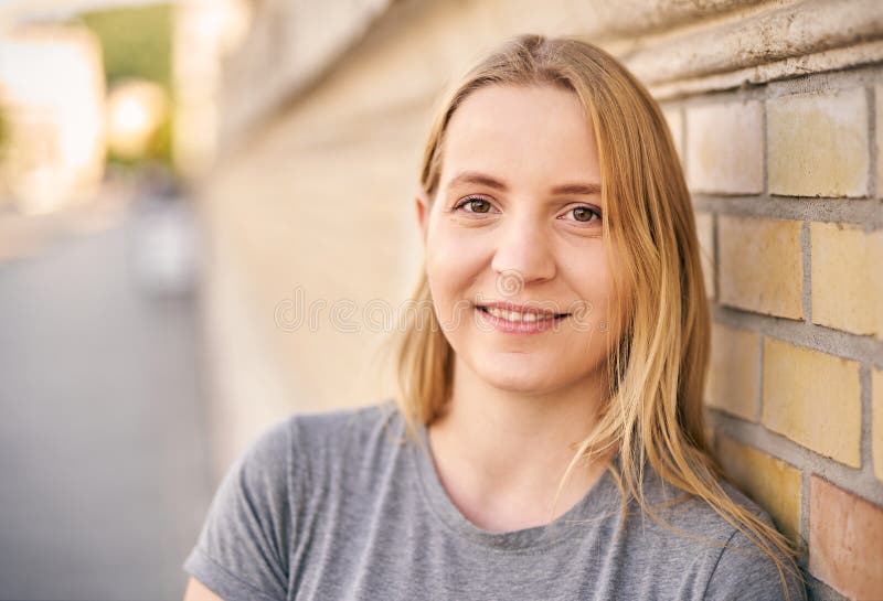 城市街道上年轻的欢快的千禧一代女子的肖像 免版税库存照片