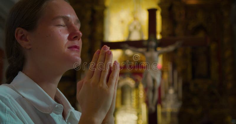 基督教妇女跪在教堂里祈祷，在耶稣受难的背景下. 特写宗教女孩