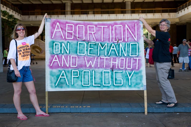 Pro-choice supporters holding large sign that reads Abortion on Demand and without Apology at a rally in front of the Hawaii State Capitol in downtown Honolulu. Pro-choice supporters holding large sign that reads Abortion on Demand and without Apology at a rally in front of the Hawaii State Capitol in downtown Honolulu