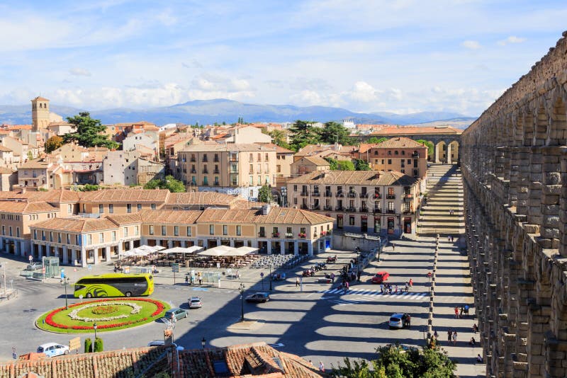 A view on the square called `Plaza de la Artilleria`, located next to the Roman Aqueduct of Segovia, from the Mirador del Acueducto in Castilla y León, Spain. The aqueduct bridge is a Roman aqueduct and one of the best-preserved elevated Roman aqueducts and the foremost symbol of Segovia, as evidenced by its presence on the city`s coat of arms. On the left the oldest church of Segovia in Romanesque style XI century, the Iglesia del Salvador. A view on the square called `Plaza de la Artilleria`, located next to the Roman Aqueduct of Segovia, from the Mirador del Acueducto in Castilla y León, Spain. The aqueduct bridge is a Roman aqueduct and one of the best-preserved elevated Roman aqueducts and the foremost symbol of Segovia, as evidenced by its presence on the city`s coat of arms. On the left the oldest church of Segovia in Romanesque style XI century, the Iglesia del Salvador.