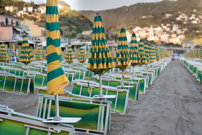 Many closed sun umbrellas and deckchairs on the sandy beach of the resort in summer. Many closed sun umbrellas and deckchairs on the sandy beach of the resort in summer.