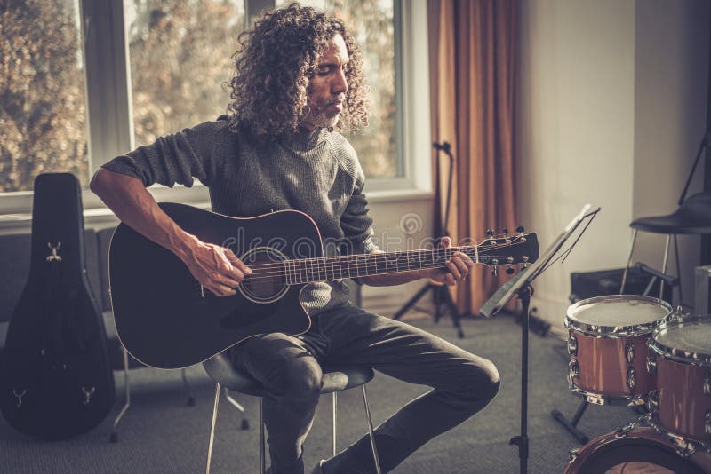 多年从事吉他音乐职业的卷发男. 免版税库存照片