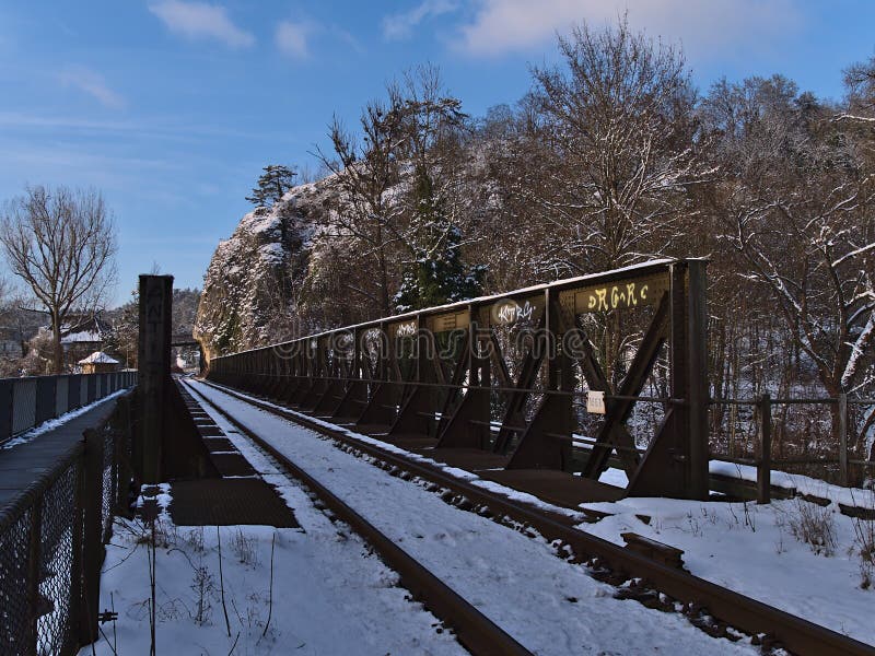 Sigmaringen, Germany - 01-09-2021: Diminishing perspective of iron railway bridge crossing Danube River with rocks and trees on sunny winter day. Sigmaringen, Germany - 01-09-2021: Diminishing perspective of iron railway bridge crossing Danube River with rocks and trees on sunny winter day.