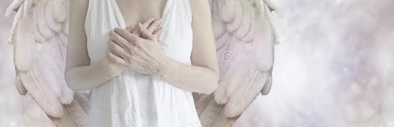 Cropped Angel showing torso in white robes with hands held over heart on a misty bokeh background with copy space on right hand side. Cropped Angel showing torso in white robes with hands held over heart on a misty bokeh background with copy space on right hand side