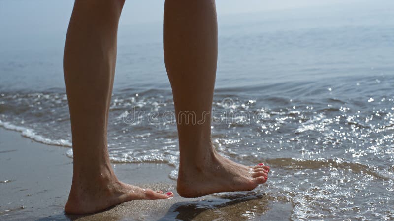 女人在阳光下跳海. 飞溅着海水的女孩腿. 免版税库存图片