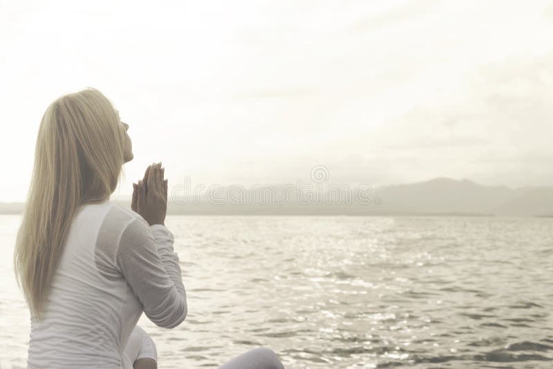 女人祈祷在海景前冥想