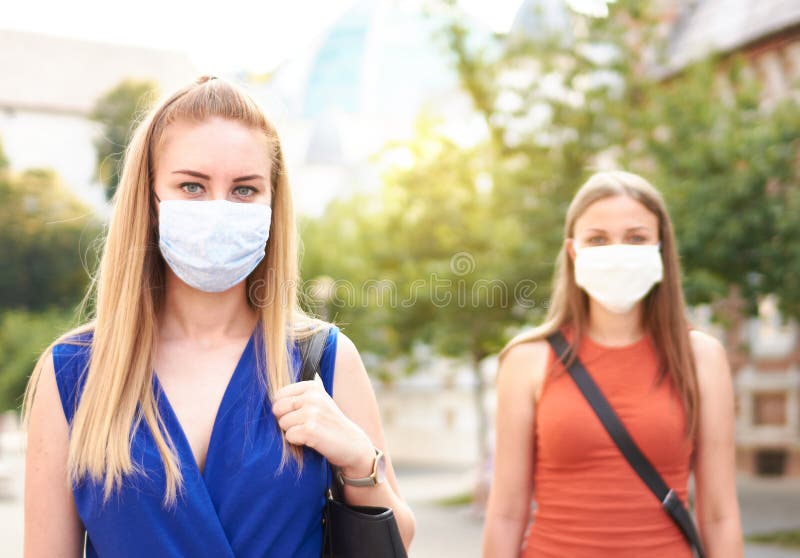 女朋友们在解封后戴着口罩散步——新的常态友谊概念，女孩们一起在 免版税库存图片