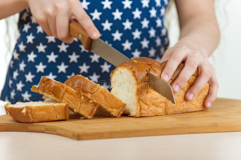 Girl cut bread with knife on wooden board. Girl cut bread with knife on wooden board.