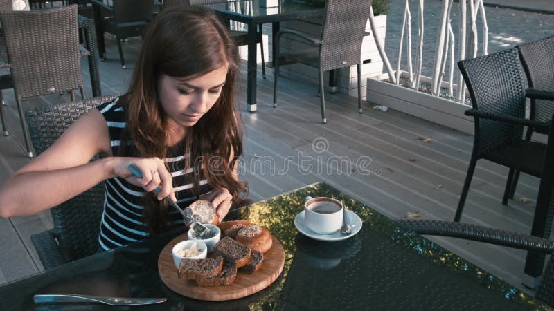 女孩吃一份百吉卷和饮用的咖啡