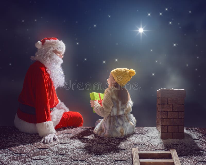 Merry Christmas and happy holidays! Cute little child girl and Santa Claus sitting on the roof and looking at snowfall. Christmas legend concept. Merry Christmas and happy holidays! Cute little child girl and Santa Claus sitting on the roof and looking at snowfall. Christmas legend concept.