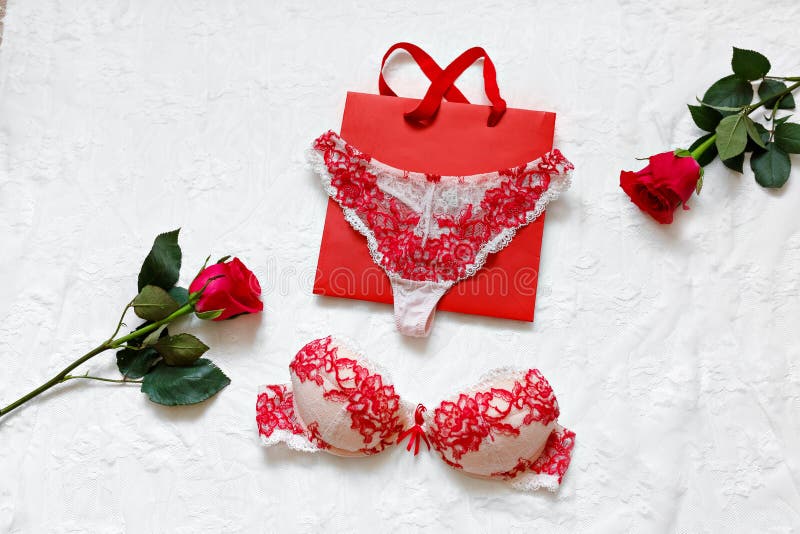 Women`s erotic underwear and red roses on white surface. Red sexy lacy lingerie on white background. Concept of love. Flat lay. Copy space. Gift of a man - a woman on March 8 and Valentine`s Day. Women`s erotic underwear and red roses on white surface. Red sexy lacy lingerie on white background. Concept of love. Flat lay. Copy space. Gift of a man - a woman on March 8 and Valentine`s Day.