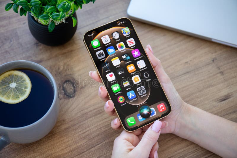 Alanya Turkey - December 6 2020: Woman hand holding iPhone 12 Pro Max Gold with home screen IOS 14 on the screen. Alanya Turkey - December 6 2020: Woman hand holding iPhone 12 Pro Max Gold with home screen IOS 14 on the screen