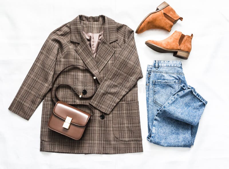 Women`s clothing set - plaid jacket, mom`s blue jeans, brown crossbody bag and suede chelsea boots on a light background, top view. Women`s clothing set - plaid jacket, mom`s blue jeans, brown crossbody bag and suede chelsea boots on a light background, top view.