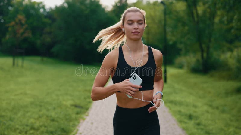 女运动员穿着运动服在公园里跑步，用耳机听音乐的智能手表 股票视频