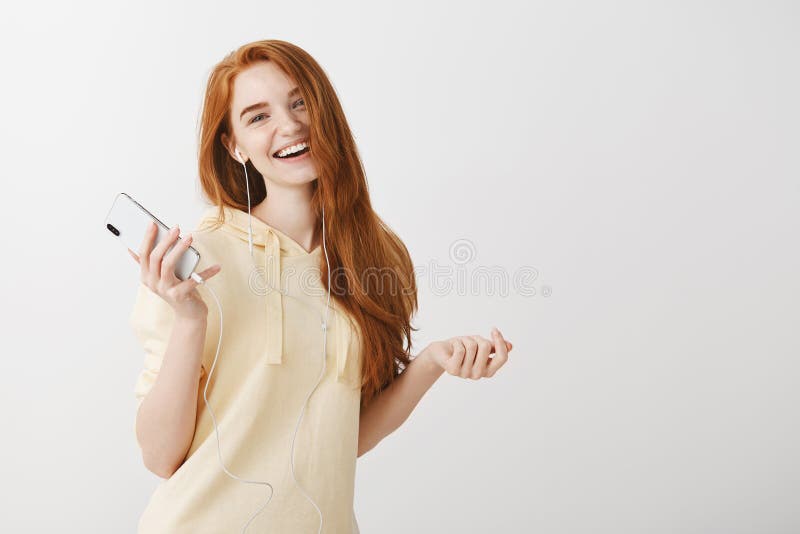 她发现了她的心情电影配乐 正面悦目女孩,藏品智能手机画象有姜头发跳舞的 免版税图库摄影 她发现了她的心情电影配乐 正面悦目女孩,藏品智能手机画象有姜头发跳舞的 免版税图库摄影
