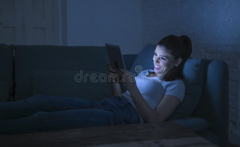 她的30s的年轻美丽和愉快的拉丁妇女拿着电视遥控在家享受客厅长沙发观看的电视节目的 免版税库存照片 她的30s的年轻美丽和愉快的拉丁妇女拿着电视遥控在家享受客厅长沙发观看的电视节目的 免版税库存照片