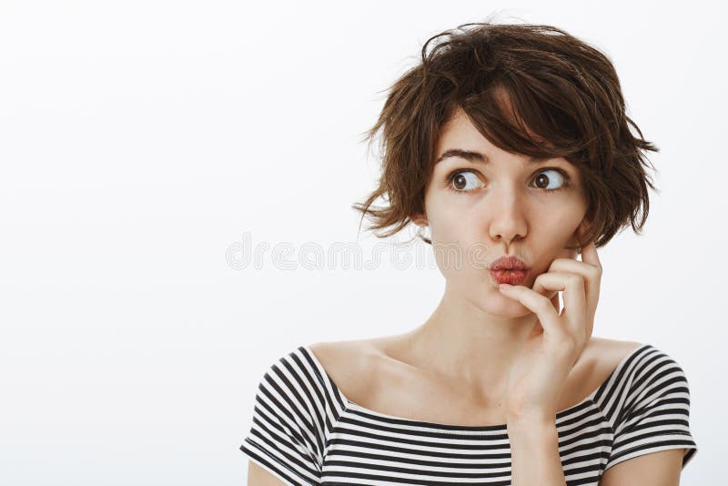好奇感情年轻女学生室内射击有逗人喜爱的杂乱发型,折叠的嘴唇和说的哇,当举行时 库存照片 好奇感情年轻女学生室内射击有逗人喜爱的杂乱发型,折叠的嘴唇和说的哇,当举行时 库存照片