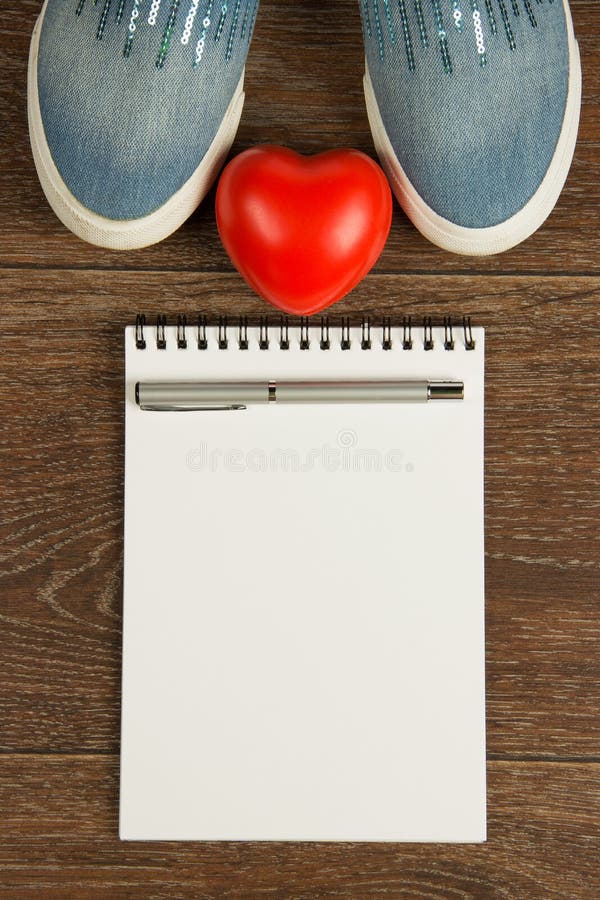 Women`s shoes, heart, pen and white notebook top view. Women`s shoes, heart, pen and white notebook top view