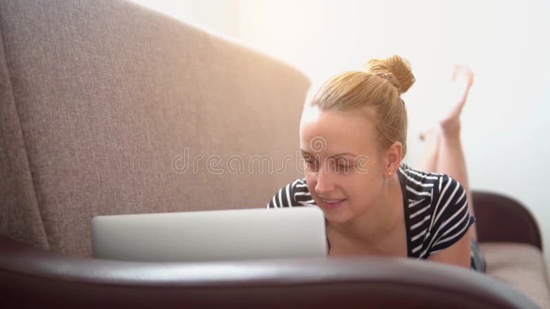 妇女在沙发和研究放松膝上型计算机，慢动作录影