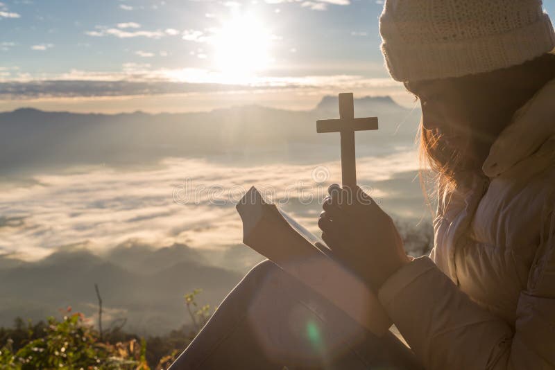 妇女祈祷给有十字架的神在与早晨日出的山背景 妇女为对祝愿的祝福有的神祈祷 免版税库存照片 妇女祈祷给有十字架的神在与早晨日出的山背景 妇女为对祝愿的祝福有的神祈祷 免版税库存照片
